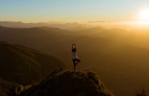 Woman stretching on a mountain top at sunris