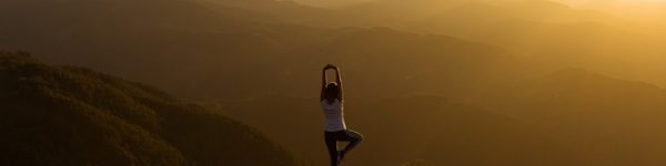 Woman stretching on a mountain top at sunris